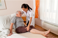 A caregiver assists her patient to lie in bed