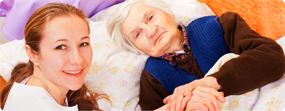 A caregiver holds the hands of her patient